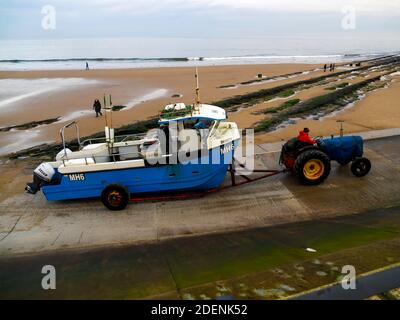 Fischer fahren einen Traktor schleppen sein Boot MH6 würde den Slipway vom Strand auf die Straße in Redcar Cleveland UK , Stockfoto