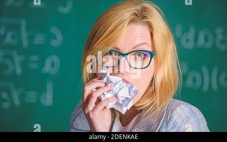 Hungrig nach Wissen. Sie war bereit, ihre Papiere zu essen. Lehrer isst ein Stück Papier mit Fehler gescheiterten Test. Frau Lehrer isst zerknittert Stück Papier Kreidetafel Hintergrund. Wissensdurst. Stockfoto