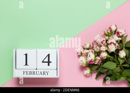 Ewiger Kalender mit Datum vom 14. Februar, Bouquet von kleinen Rosen auf zweifarbigem Hintergrund rosa und grün. Flach liegend. Draufsicht. Valentinstag ce Stockfoto