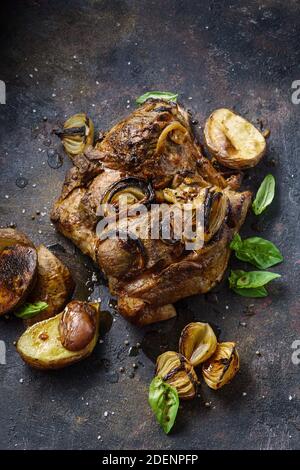 Ganze gebackene Schweineschulter mit Gemüse und Gewürzen auf einem Alte Pfanne Stockfoto