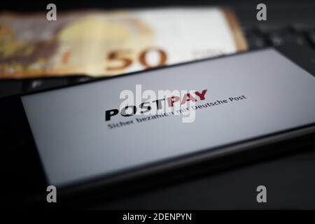 Viersen, Deutschland - 9. April. 2020: Nahaufnahme des Handybildschirms mit Logo-Schriftzug des Postpay Payment Providers auf Computertastatur, verschwommene Euro m Stockfoto