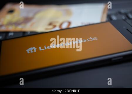 Viersen, Deutschland - 9. April. 2020: Nahaufnahme des Handybildschirms mit Logo-Schriftzug des Lieferando Food Delivery Service auf Computertastatur, verschwommen Stockfoto