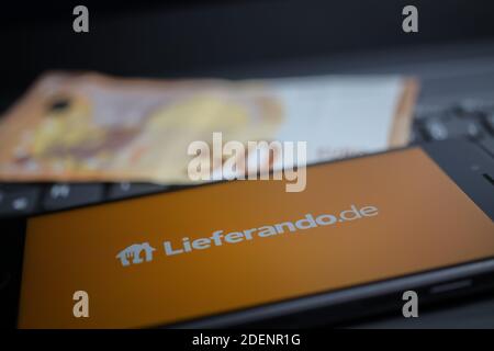 Viersen, Deutschland - 9. April. 2020: Nahaufnahme des Handybildschirms mit Logo-Schriftzug des Lieferando Food Delivery Service auf Computertastatur, verschwommen Stockfoto