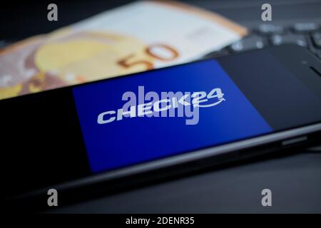 Viersen, Deutschland - 9. April. 2020: Nahaufnahme des Handybildschirms mit Logo-Schriftzug des Check24 Vergleichsportals auf Computertastatur, 50 Euro Geld Stockfoto