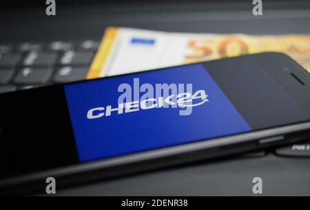 Viersen, Deutschland - 9. April. 2020: Nahaufnahme des Handybildschirms mit Logo-Schriftzug des Check24 Vergleichsportals auf Computertastatur, 50 Euro Geld Stockfoto