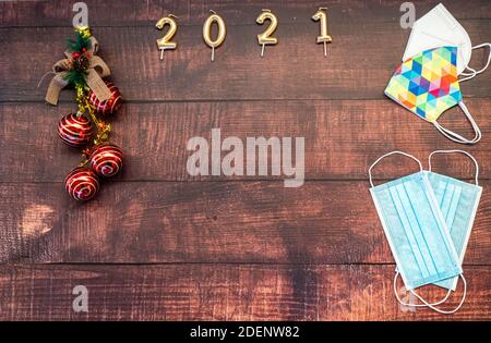 Jahr 2021 auf horizontalem dunklen Holzhintergrund mit Weihnachtsdekoration Und Masken gegen covid Stockfoto