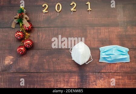 Jahr 2021 auf horizontalem dunklen Holzhintergrund mit Weihnachtsdekoration Und Masken gegen covid Stockfoto
