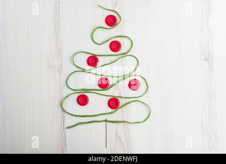 Nähthema kreatives Flat Lay Design: Weihnachtsbaum aus Nadel, Faden und Knöpfen auf Holzfläche Stockfoto