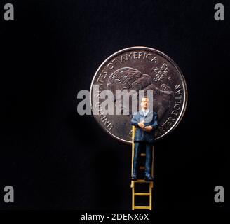 Miniatur Geschäftsmann an der Spitze der Leiter vor Des Quartals Stockfoto