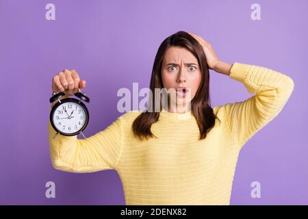 Foto Porträt von verärgert Frau läuft spät mit schwarzer Uhr In einer Hand berühren Kopfhaar isoliert auf lebendige lila Farbiger Hintergrund Stockfoto