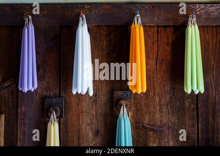 Bunte Kegel Kerzen hängen an rustikalen Holzwand Stockfoto