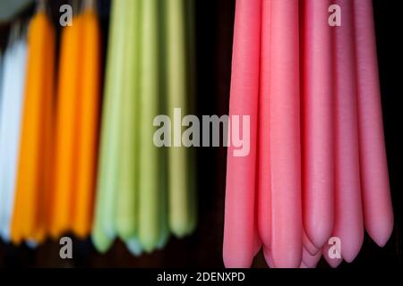 Bunte Kegel Kerzen hängen an rustikalen Holzwand Stockfoto