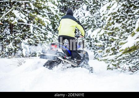 Sportler fährt ein Schneemobil in den Bergen. Schneemobil im Schnee. Konzept Wintersport. Der Mensch fährt Schneemobil in den Bergen. Pilot auf einer Sportart Stockfoto