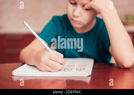 Nahaufnahme des Schuljungen lernen Mathematik bei Hausaufgaben, kleine DoF, Fokus auf die Hand mit Bleistift. Kind, das kreative Übungen entwickelt Stockfoto