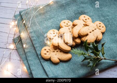 Ein Stapel Lebkuchen oder Ingwer-Mann auf einem weißen Tisch und grünes Tuch mit weihnachtsbeleuchtung Stockfoto