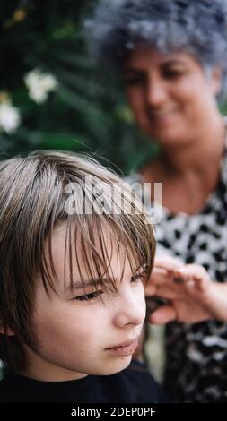 Stock Foto von jungen immer seine Frisur von einer glücklichen Frau im Garten. Er schaut nach vorne. Stockfoto