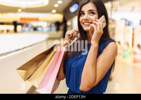 Mädchen sprechen am Telefon beim Einkaufen, Porträt einer Frau mit Paketen im Geschäft Stockfoto