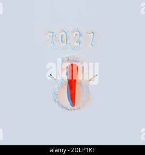 Ein Schneemann aus Mehl mit Karotten und Streichhölzern. Neujahrskonzept Postkarte 2021 Stockfoto