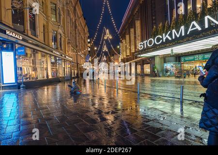 Helsinki, Finnland 30. November 2020 Stadtzentrum, historische Gebäude und eine vorbeifahrende grüne Straßenbahn. Brennende Laternen und Reflexionen nach dem Regen. Hochwertige Fotos Stockfoto