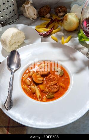 Cremige italienische Wurstsuppe mit Mozzarella-Käsezwiebeln und Paprika Serviert mit einem Glas Rotwein Stockfoto