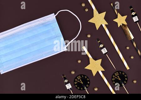 Konzept für Neujahrsfeier in Corona Virus Zeiten mit silvester Party Dekoration mit medizinischer Gesichtsmaske auf dunklem Hintergrund Stockfoto