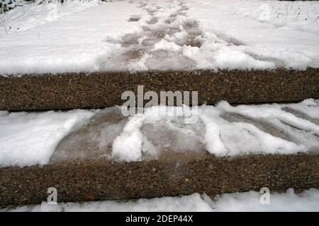 Outdoor-Stufen mit Schnee und Schuhabdrücke und Hundepfoten in ihm bedeckt. Der Schnee wurde nicht weggeräumt. Rutschiger Boden ist riskant und gefährlich. Stockfoto