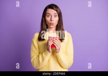 Foto-Porträt der überraschten Frau hält Tasse heißen Tee Isoliert auf lebhaft violettem Hintergrund Stockfoto