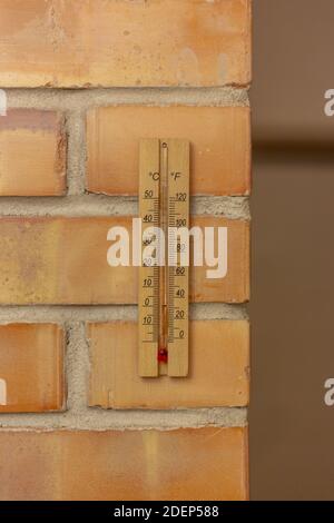 Hölzernes Thermometer auf einer Ziegelwand Stockfoto