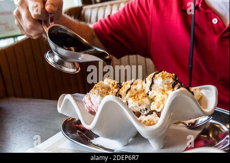 Banane Split mit Mann Gießen heiße Schokolade Sirup auf Stockfoto