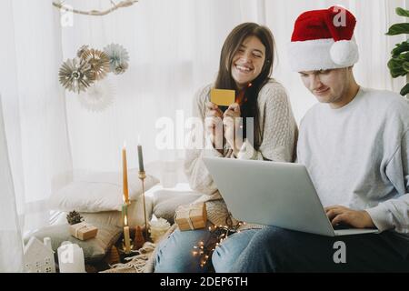 Weihnachtsverkauf und Online-Home-Shopping. Happy stilvolle Familie mit Laptop und Kreditkarte Online-Shopping am Black Friday, sitzen in modernen Zimmer mit Witz Stockfoto