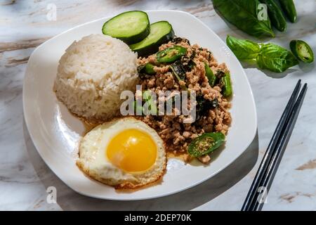 Phat Krapow Mu SAP auch bekannt als Rührgebratenes Thai-Basilikum Schweinefleisch mit Austernsauce serviert mit weißem Reis und ein Spiegelei sunnyside oben Stockfoto