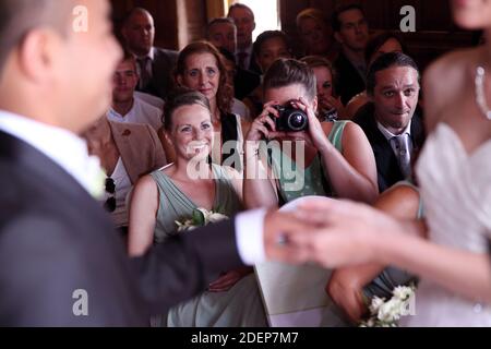 Sitzender Hochzeitsgast mit kompakten SLR-Kamera Fotos Hochzeitszeremonie Als Braut und Bräutigam halten Hände für ihre Hochzeit Gelübde Stockfoto