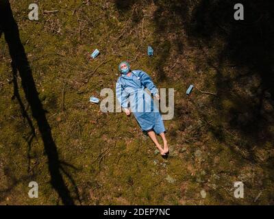 Luftaufnahme: Müde Ärztin oder Krankenschwester berührt Kopf in Ruhe im Wald Stockfoto