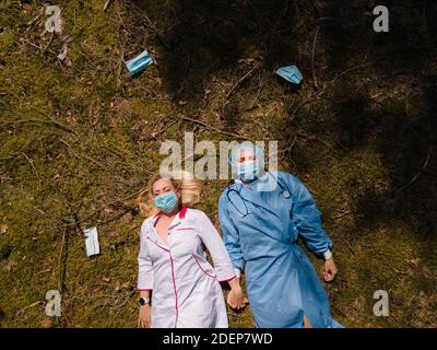 Zwei erschöpfte Mediziner in OP-Masken liegen im Wald Stockfoto