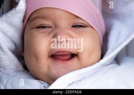 Säugling, Kindheit, Emotion Konzept - Nahaufnahme von niedlichen lächelnd Porträt Gesicht von braunen Augen mollig Neugeborenen wach zahnlos Baby 6-9 Monate alt Blick auf Stockfoto