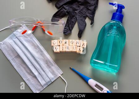 Die Werkzeuge, die Sie brauchen, um sich vor dem Coronavirus in einem flachen Lay mit OP-Maske, Handschuhe, Handdesinfektionsmittel, Schutzbrille und einer Thermik zu schützen Stockfoto