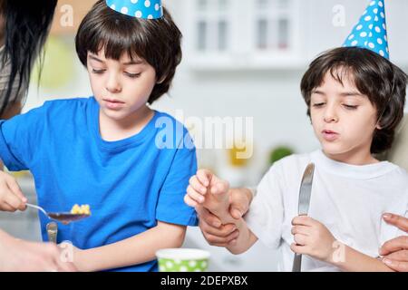 Zwei nette kleine Brüder in Birtday Caps essen, Abendessen, während der Feier Geburtstag zusammen zu Hause. Kinder, Feier Konzept Stockfoto