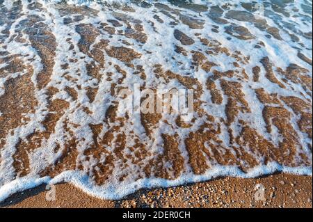 Nahaufnahme der Flutwassersurfen auf dem Sandstrand. Selektiver Fokus Stockfoto