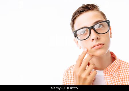 Junger Mann mit nachdenklichen Blick, Kerl hält Hand in der Nähe Gesicht, Junge mit Brille im Studio auf weißem Hintergrund Stockfoto