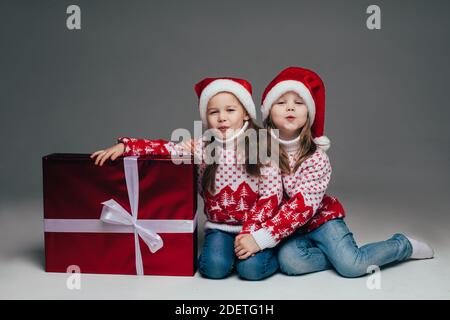 Nette Schwestern in Santa Hüte mit Geschenk. Stockfoto