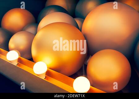 Goldene farbige Kugeln durch elektrische Lampen beleuchtet. Modernes Design Hintergrund Stockfoto