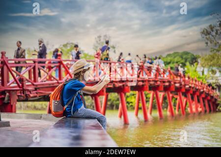 Kaukasischer Junge Tourist auf dem Hintergrund der Roten Brücke in der Öffentlichkeit park Garten mit Bäumen und Reflexion in der Mitte von Hoan Kiem See in der Innenstadt von Hanoi Stockfoto