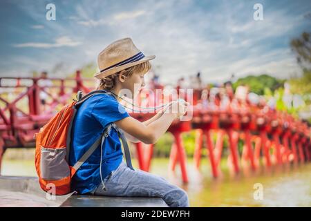 Kaukasischer Junge Tourist auf dem Hintergrund der Roten Brücke in der Öffentlichkeit park Garten mit Bäumen und Reflexion in der Mitte von Hoan Kiem See in der Innenstadt von Hanoi Stockfoto