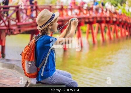 Kaukasischer Junge Tourist auf dem Hintergrund der Roten Brücke in der Öffentlichkeit park Garten mit Bäumen und Reflexion in der Mitte von Hoan Kiem See in der Innenstadt von Hanoi Stockfoto