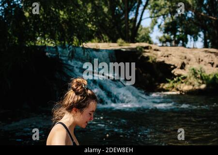 Nahaufnahme von teen Mädchen zu Fuß in der Nähe eines kleinen stehen Wasserfall Stockfoto