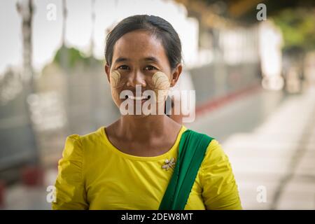 Porträt einer lächelnden Frau mit Blattmarkierungen auf ihrem Gesicht von thanaka, Mandalay, Myanmar Stockfoto