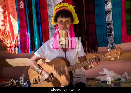 Ältere burmesische Frau aus Kayan Stamm (AKA Padaung, langhalsig) spielen Musikinstrument ähnlich Gitarre, in der Nähe von Loikaw, Kayah Staat, Myanmar Stockfoto