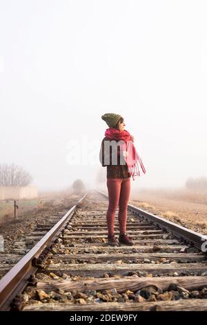 Nachdenkliche Frau, die auf einer nebligen Eisenbahn steht, während sie wegschaut Stockfoto