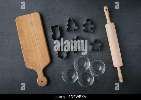 Weihnachts-Plätzchen-Ausstecher mit Schneidebron und Rolling Pin auf Dunkle Schieferstruktur Stockfoto