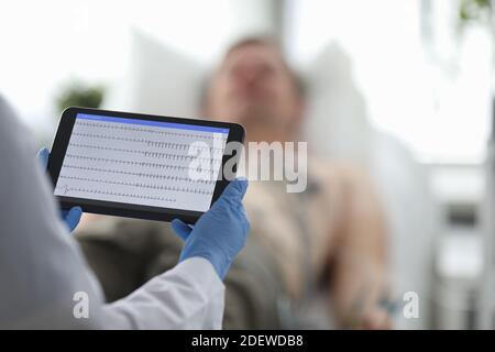 Arzt mit ekg-Monitor steht vor dem Patienten in Hintergrund Stockfoto